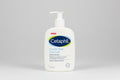 Cetaphil Gentle Skin Cleanser bottle with a crumpled foil top on a wooden surface.